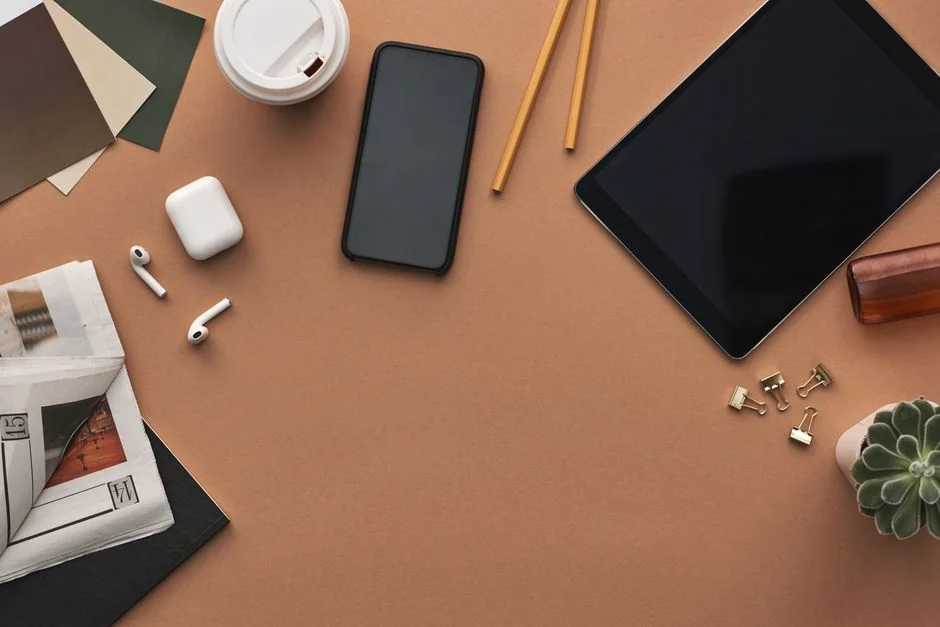 A cozy modern workspace featuring a laptop displaying a website, a smartphone, and books on shelves.